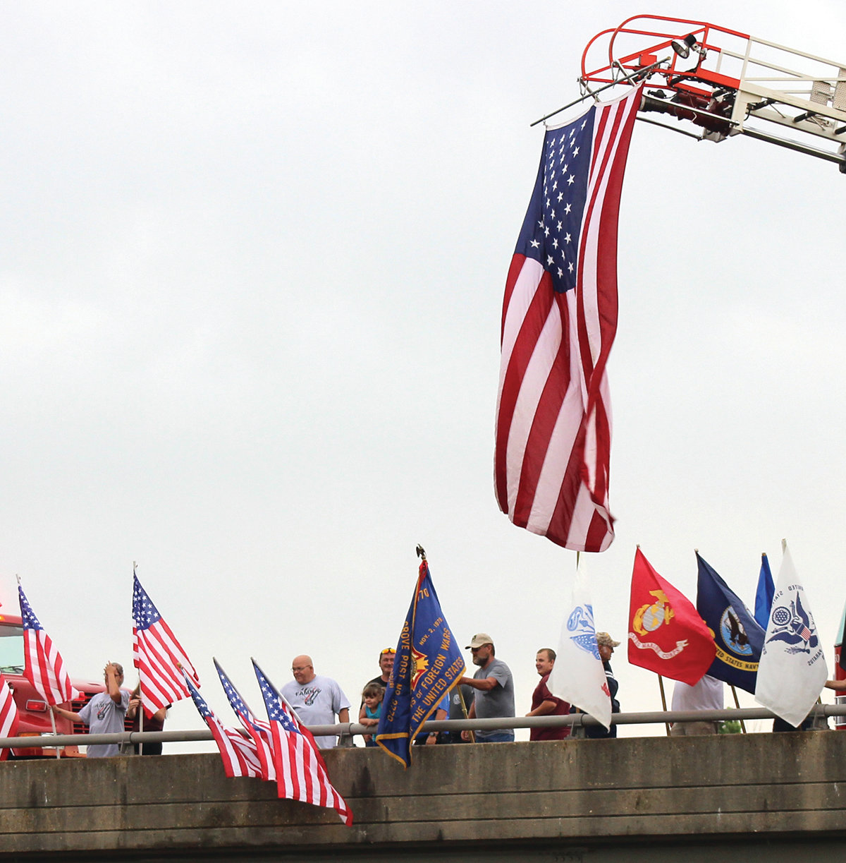 Members of both the American Legion Post No. 30 and VFW Post No. 3770 hold flags in support of the country and military on a Mountain Grove overpass as the Vietnam War Traveling Memorial Wall goes by the exit.